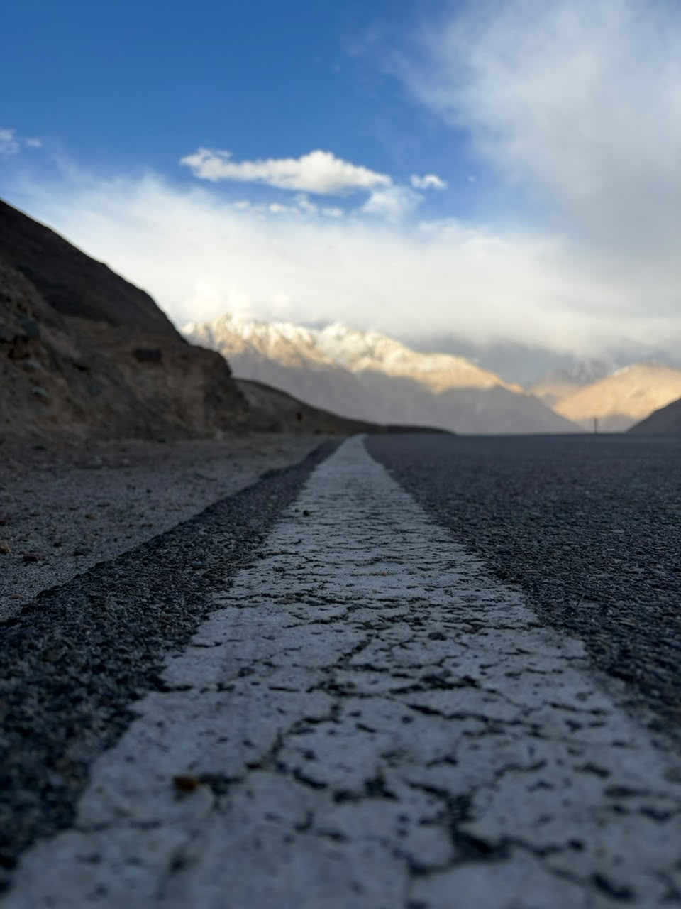 Empty Ladakh highway leading toward snow-capped peaks at first light