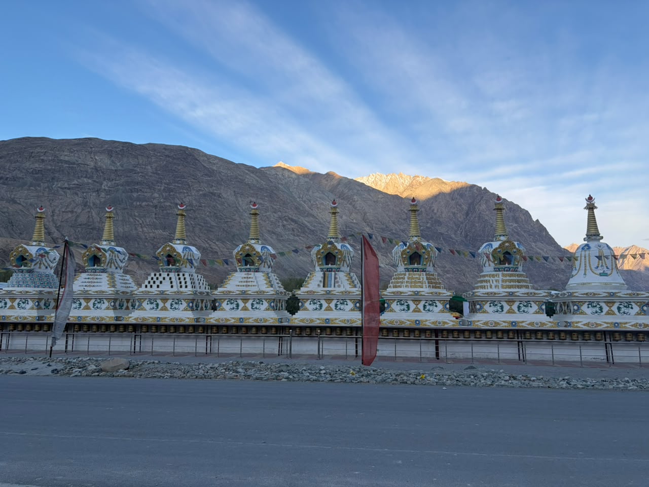 Row of Buddhist stupas and prayer wheels below the mountains in Nubra Valley, Ladakh