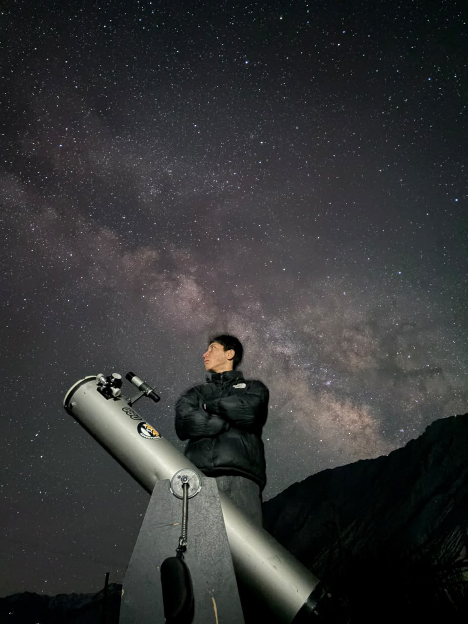 Stargazer beside a Newtonian telescope under a star-filled Ladakh sky