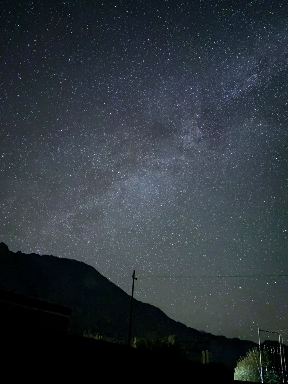 Star-filled Ladakh night sky above a dark mountain silhouette